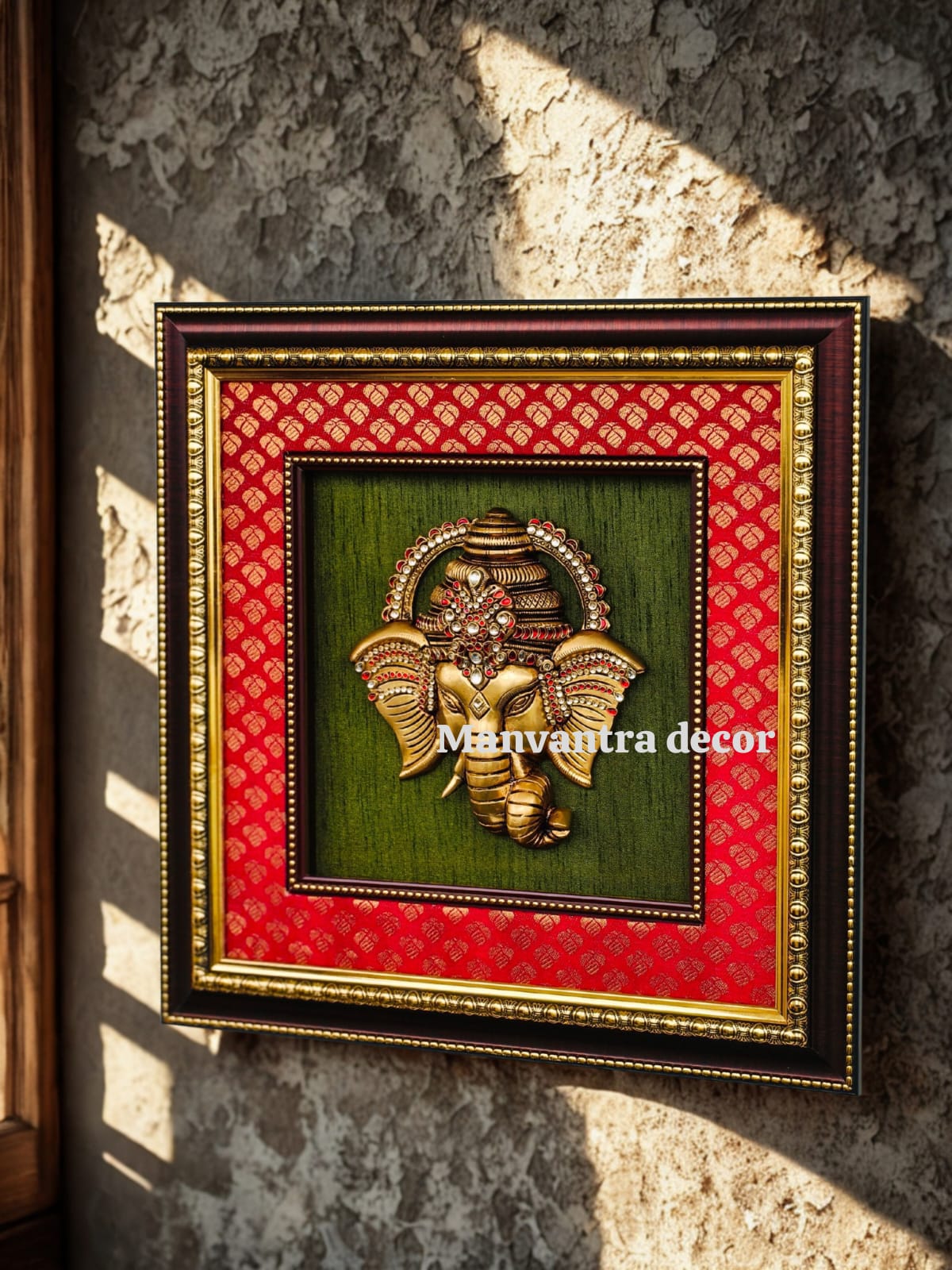 Brass Ganesha wall hang with stonework mounted on red brocade silk double frame